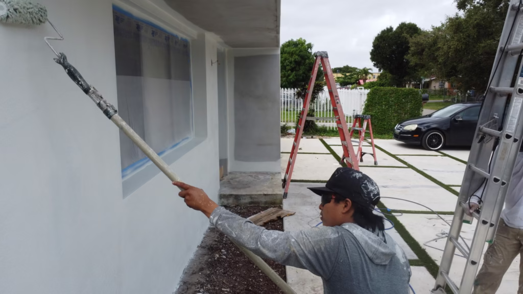 Painter rolling paint on an exterior stucco wall